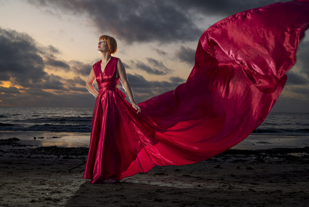 Frau in rotem Kleid bei Sonnenuntergang am Meer in Ibiza